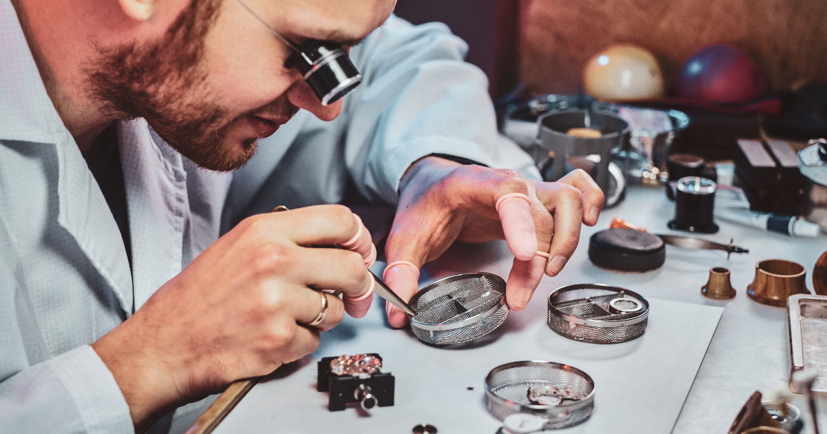 młody zegarmistrz naprawiający mały mechanizm zegarka