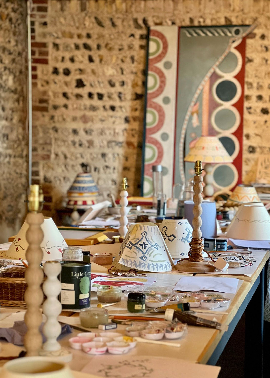 Ekran laptopa wyświetlający lekcję online malowania kwiatów na ceramice z paletą farb obok