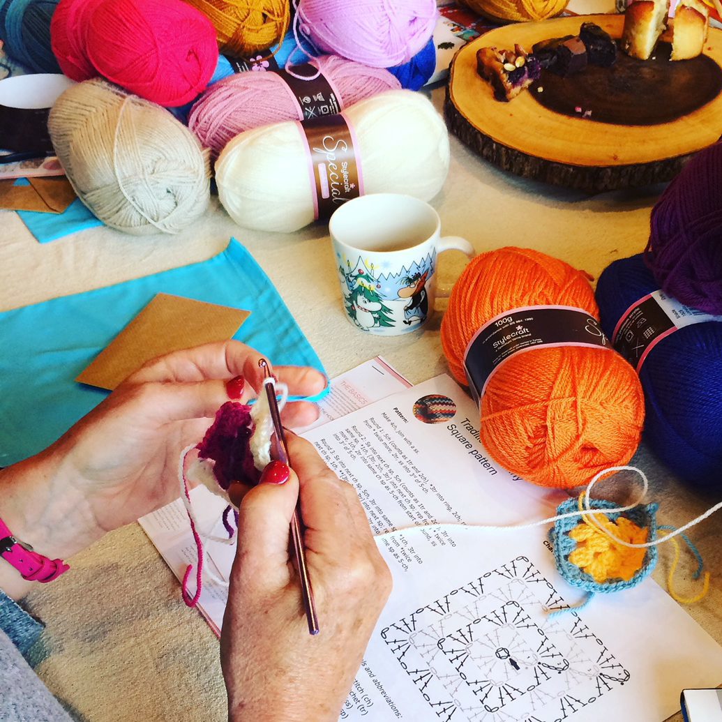 Tkaczka obsługująca krosno z kolorowymi nićmi tworząc wzorzysty gobelin w pracowni