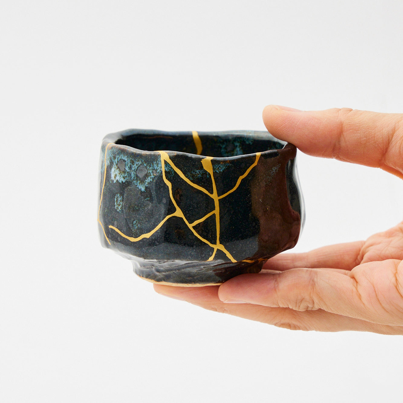 wyjmowanie pękniętej wazy z pieca rękawice trzymające pękniętą wazę nad żarzącym się palnikiem