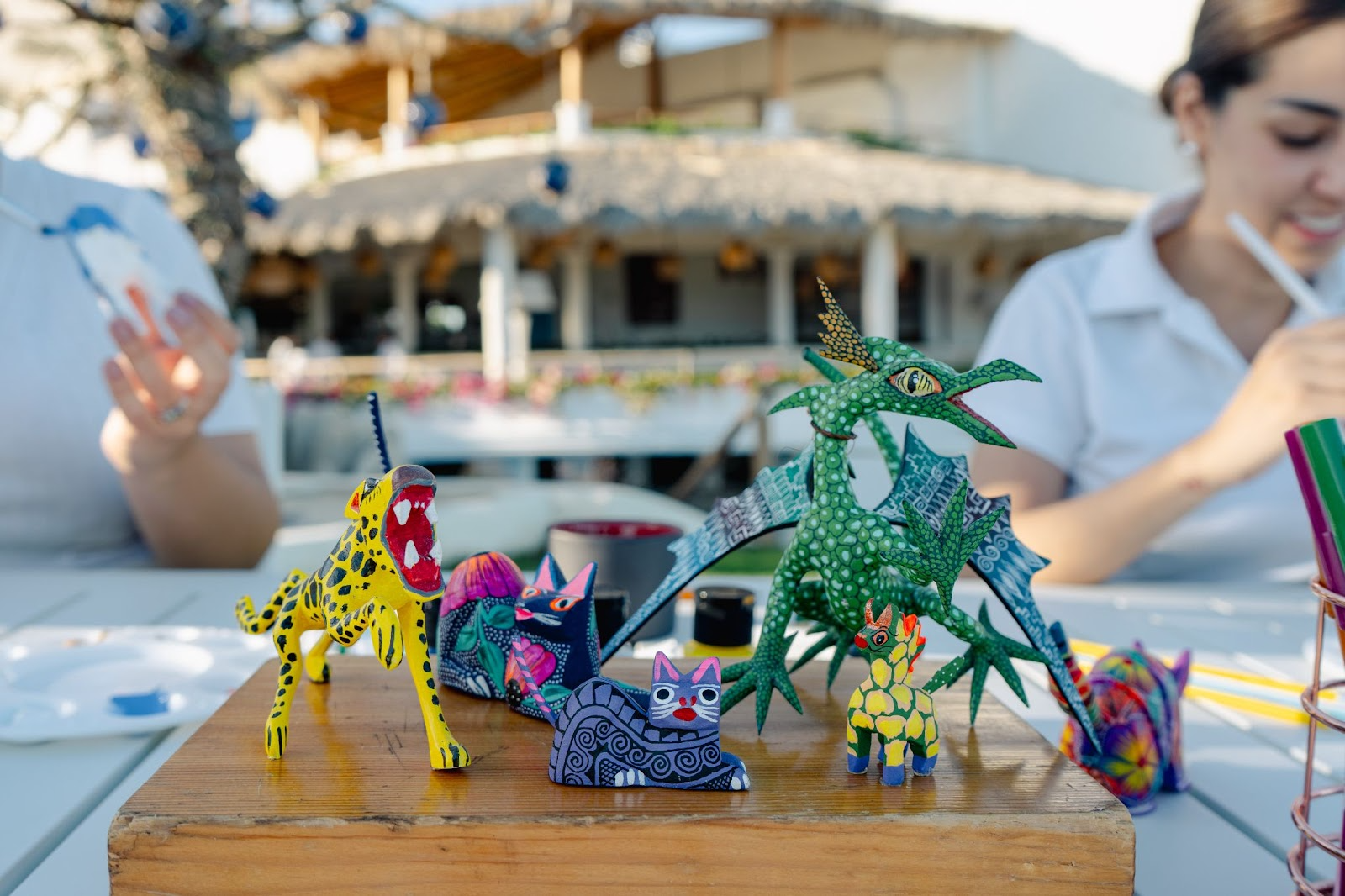 Różnorodne dzieła rzemiosła artystycznego na stole warsztatowym z narzędziami i artystami w tle